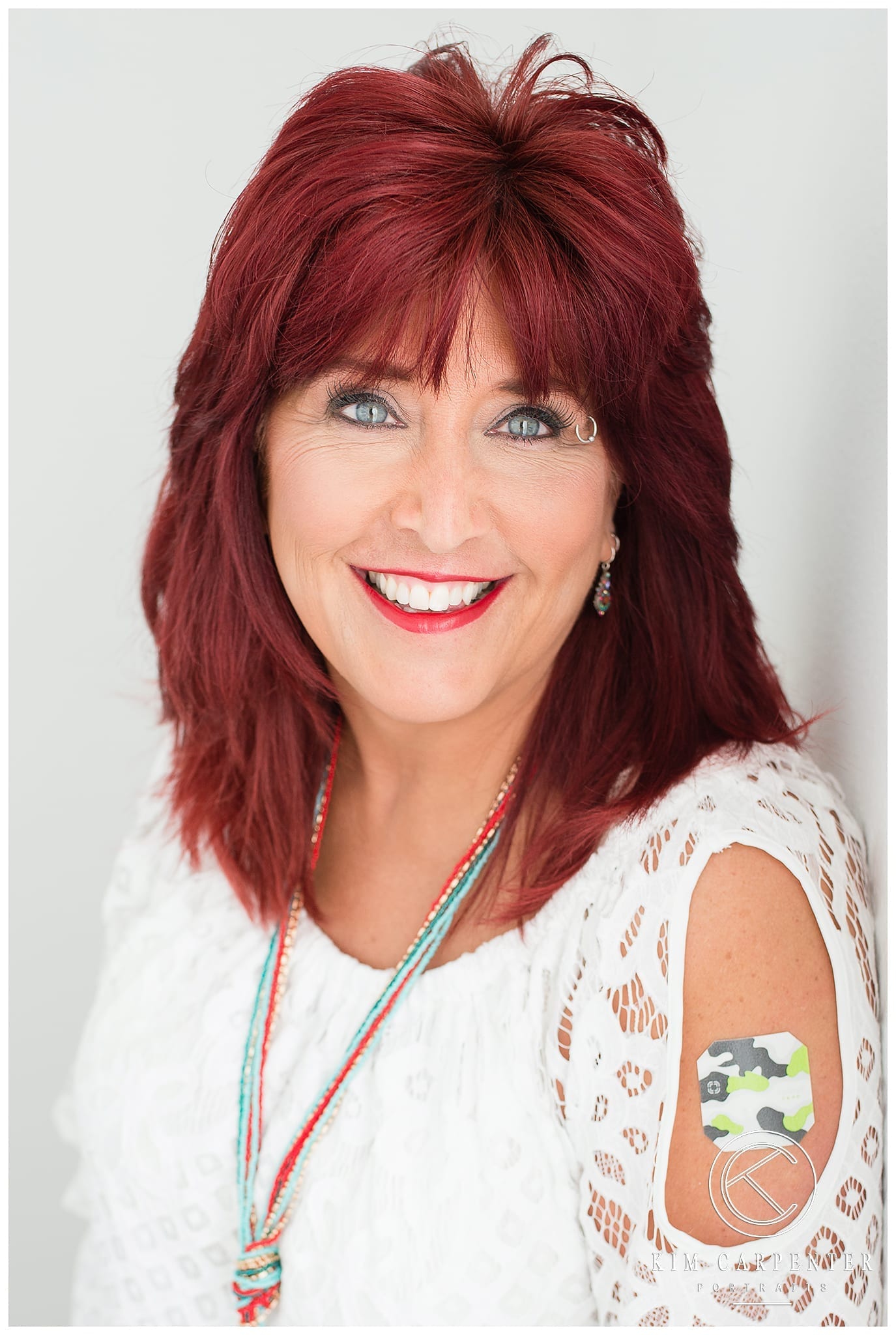 Woman wearing a white lace shirt and a Thrive sticker is showing on her shoulder. Lakeland Photographer, professional headshots