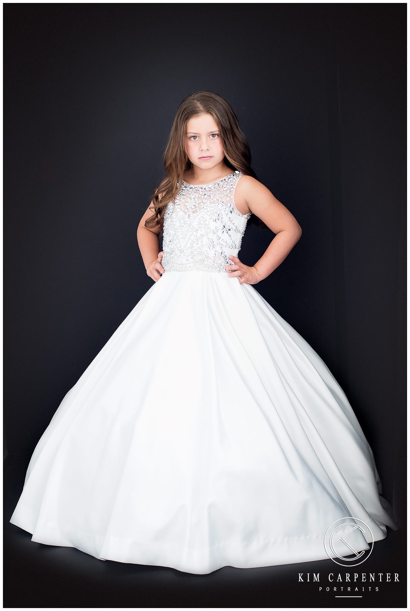 beautiful little girl in a long white gown with a black background