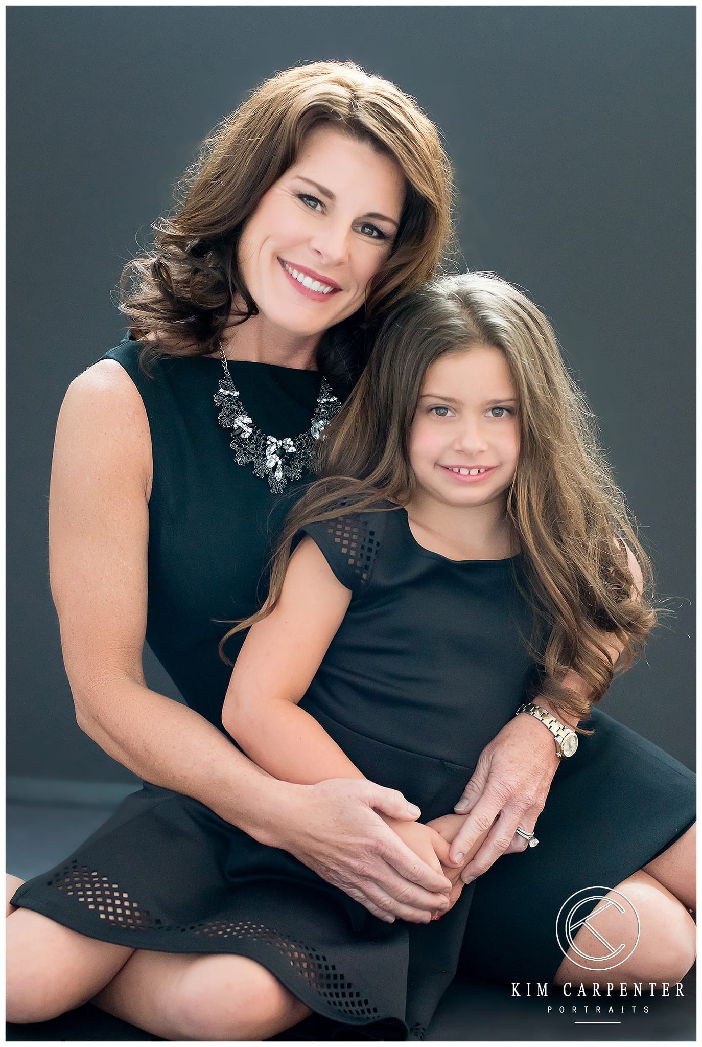 Photo of a Mother and Daughter in beautiful black dresses with a black background and backlight
