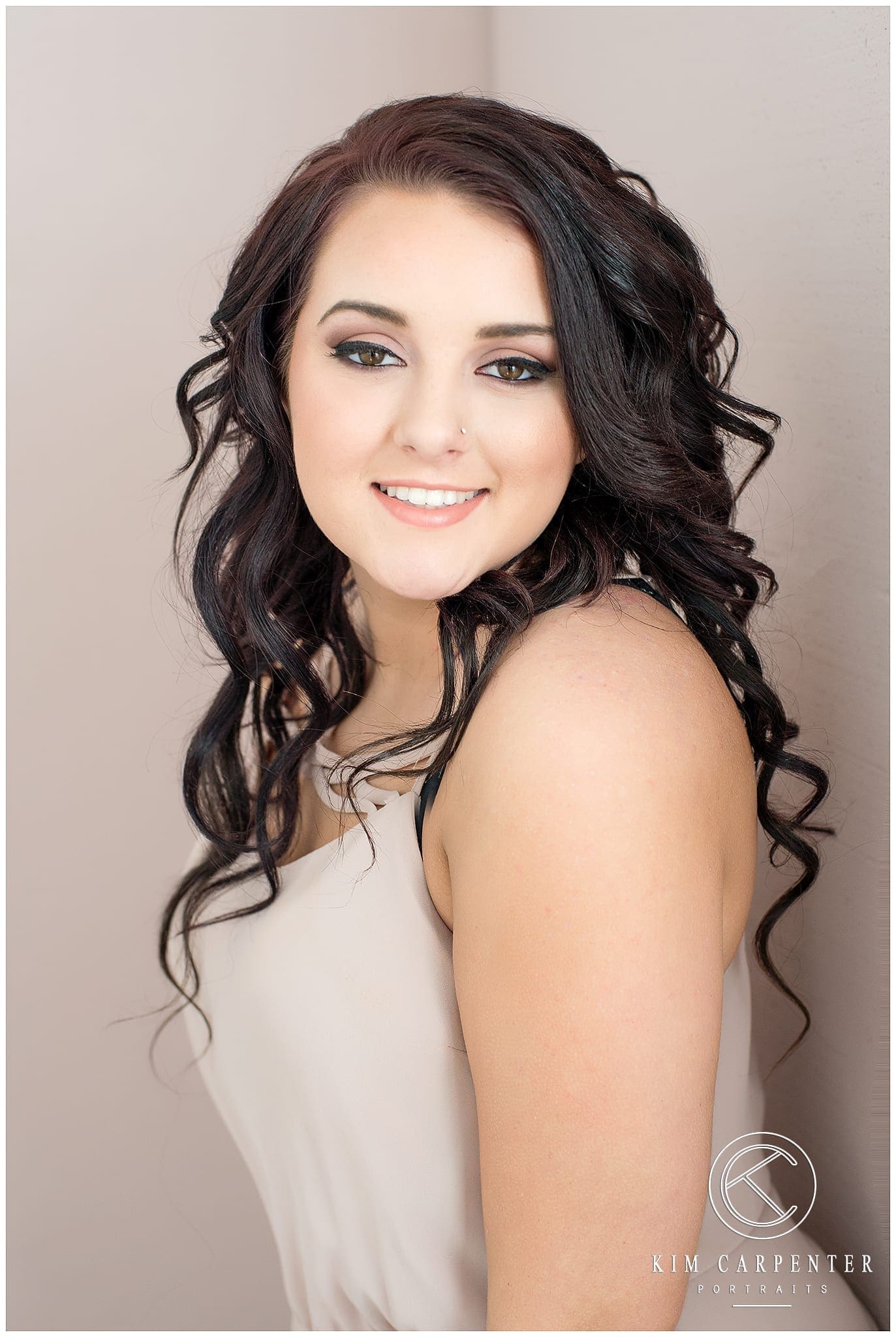 Senior with brown hair smiling at camera for her senior portraits.