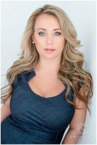 Woman leaning against wall wearing a blue dress.