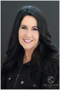 A close picture of a woman with black curls and a black shirt.