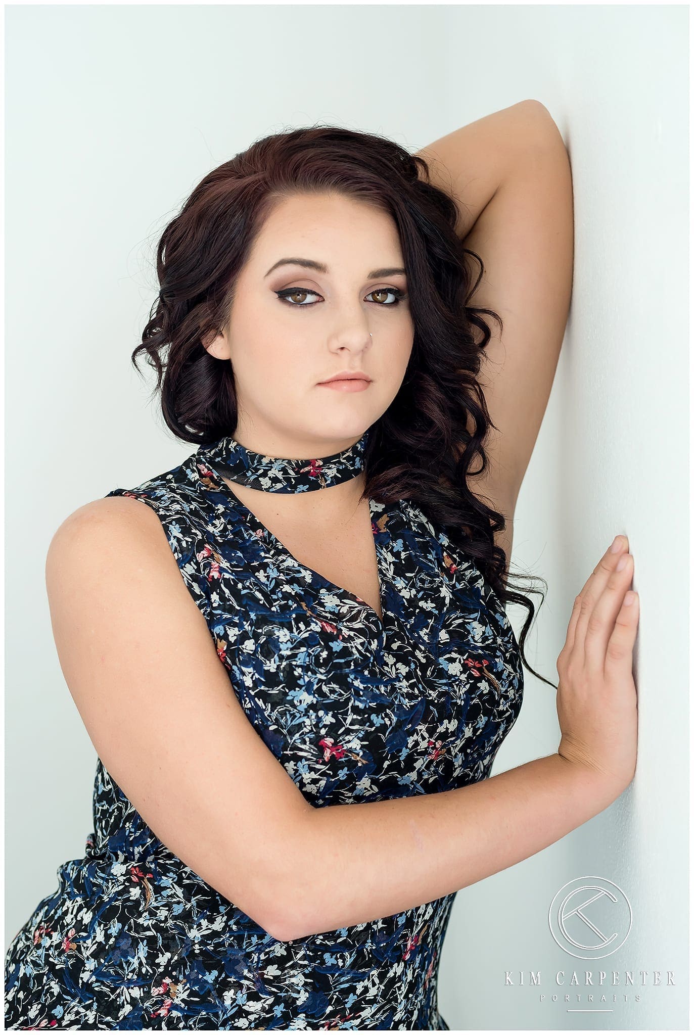 A senior portrait of a high school girl leaning against a wall.