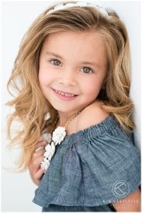 Girl smiling at camera while leaning against a wall.