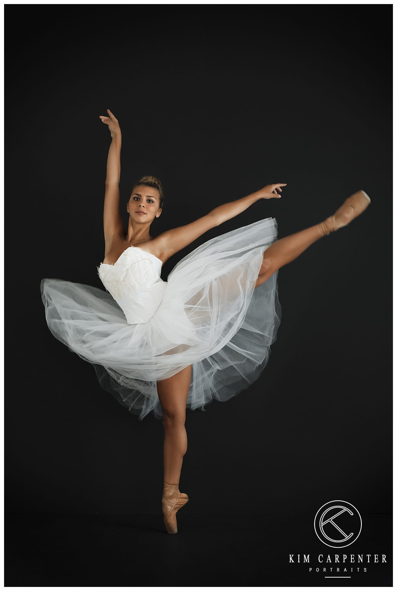 A black background with a dancer dressed in white with one leg high.