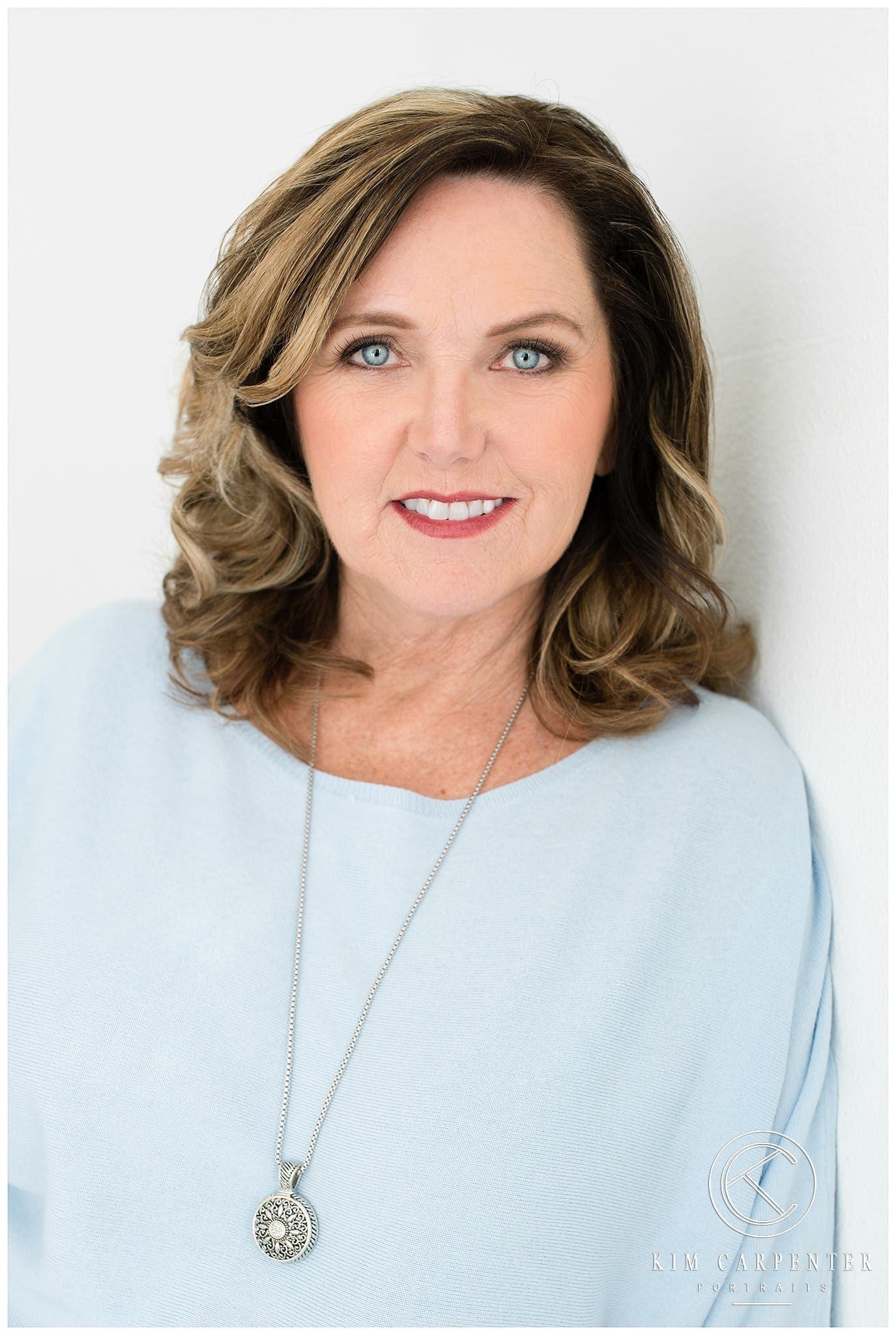 Woman wearing a silver necklace smiling for a professional headshot.