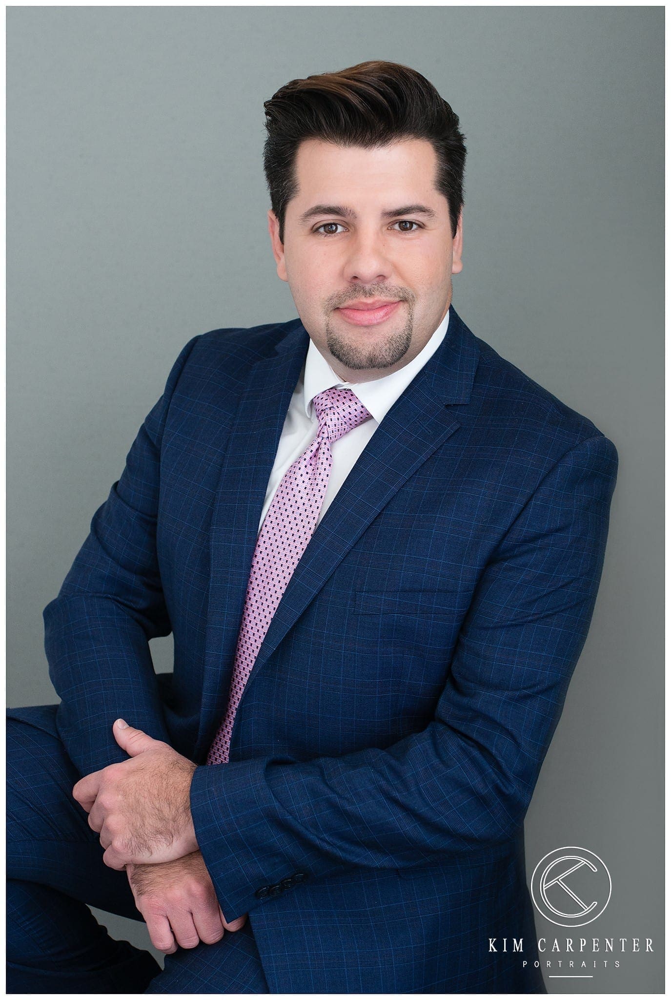 Man smiling with arms crossed getting a professional headshot taken. 